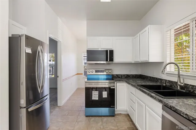 a kitchen with stainless steel appliances granite countertop a refrigerator stove and sink