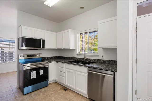 a kitchen with granite countertop a sink stove top oven and microwave