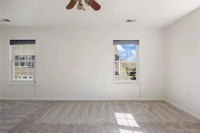 an empty room with windows and fan