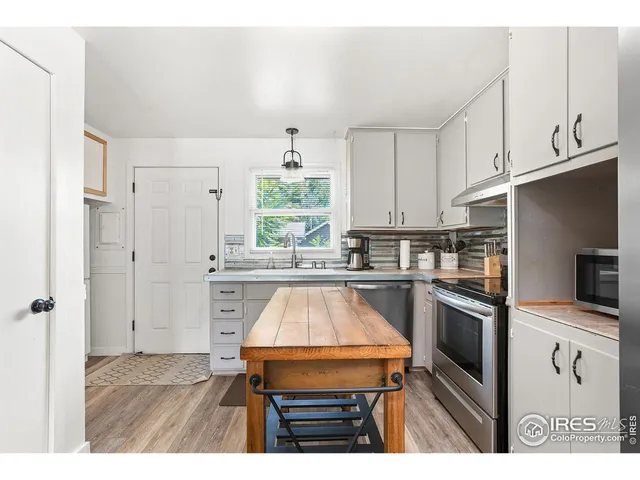 a kitchen with kitchen island granite countertop a stove a sink dishwasher and a refrigerator with wooden floor