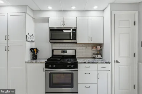 a kitchen with granite countertop white cabinets stainless steel appliances and sink