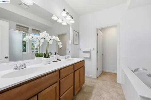 a spacious bathroom with a granite countertop sink a large mirror and a bathtub