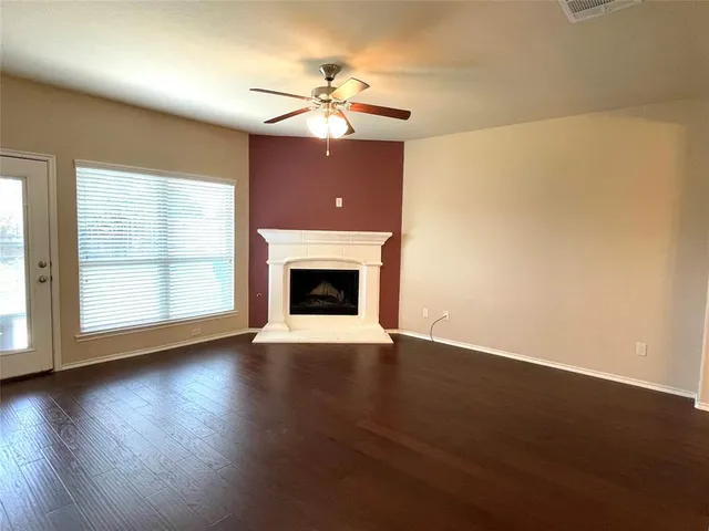 a view of an empty room with wooden floor fireplace and a window