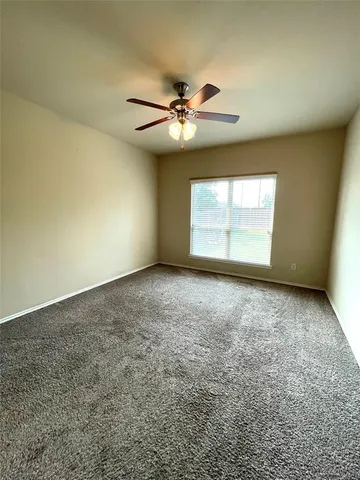 an empty room with a window and a ceiling fan