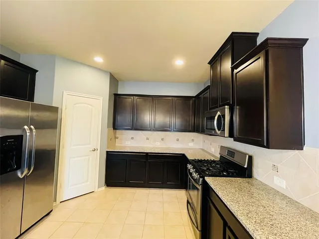a kitchen with stainless steel appliances granite countertop a sink and a refrigerator