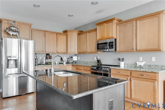 a kitchen with stainless steel appliances granite countertop a refrigerator a sink a stove a microwave and cabinets