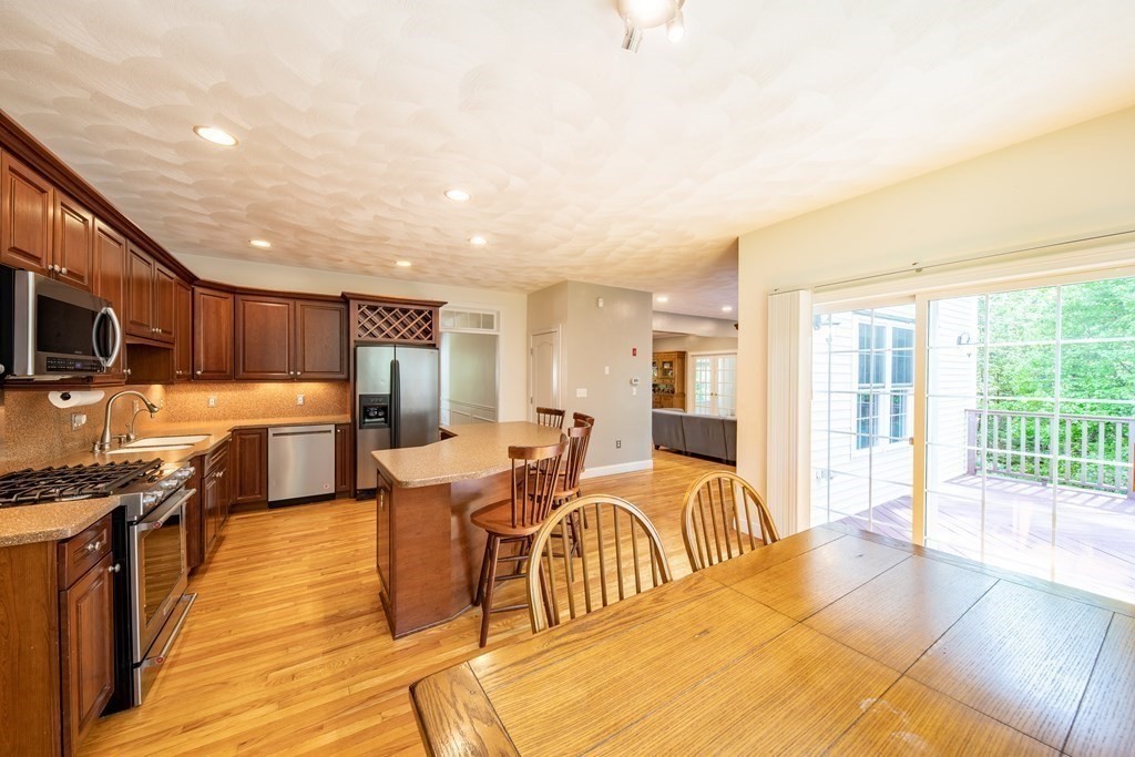 101 Stonefence Road Lunenburg, MA 01462 - Photo 19 of 41 a open kitchen with stainless steel appliances granite countertop a stove top oven a sink dishwasher a dining table and chairs with wooden floor