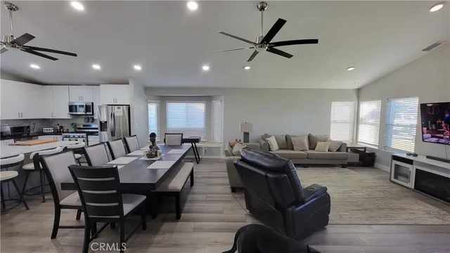 a living room with furniture kitchen view and a wooden floor