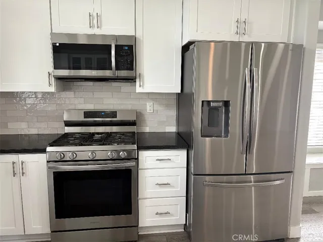a kitchen with stainless steel appliances white cabinets white stove and microwave
