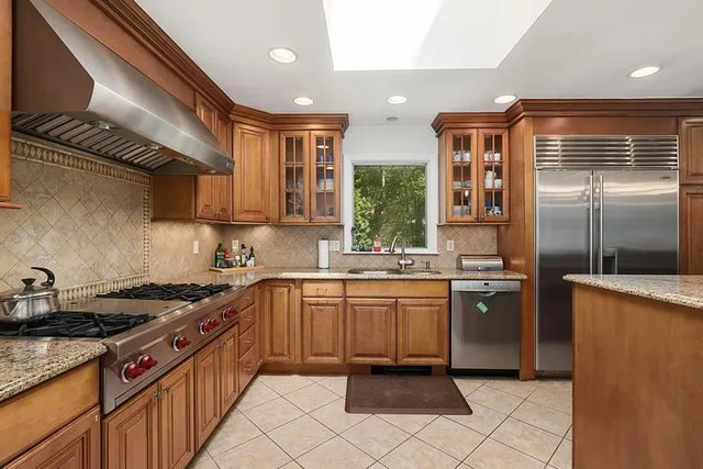 a kitchen with stainless steel appliances granite countertop a sink a stove a refrigerator and cabinets