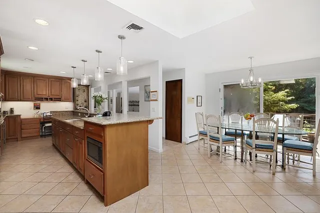 a large kitchen with stainless steel appliances kitchen island granite countertop a table and chairs