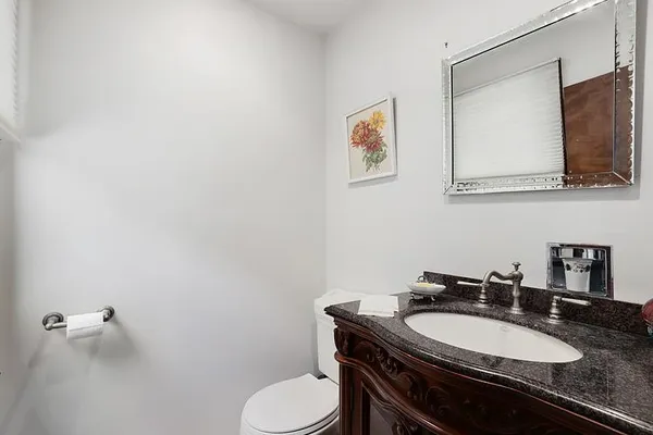 a bathroom with a granite countertop toilet sink and mirror