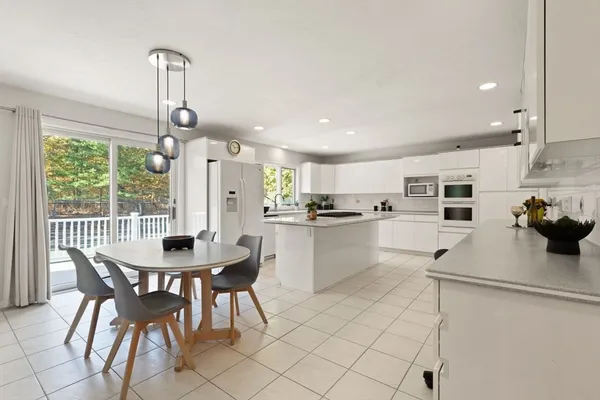 a kitchen with stainless steel appliances kitchen island granite countertop a dining table chairs and white cabinets
