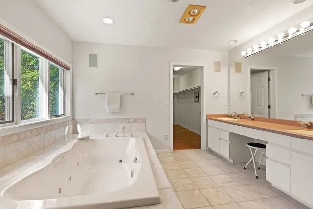 a spacious bathroom with a tub sink and mirror