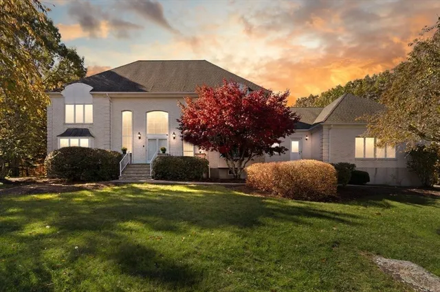 a front view of a house with a garden and trees