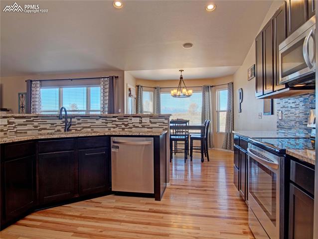 11601 Rio Secco Road Peyton, CO 80831 - Photo 21 of 36 Kitchen with Stainless Steel Appliances, Glass Tile Backsplash, Granite Countertops and pantry