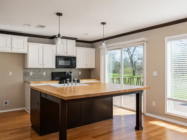 a kitchen with a sink a large window appliances and cabinets
