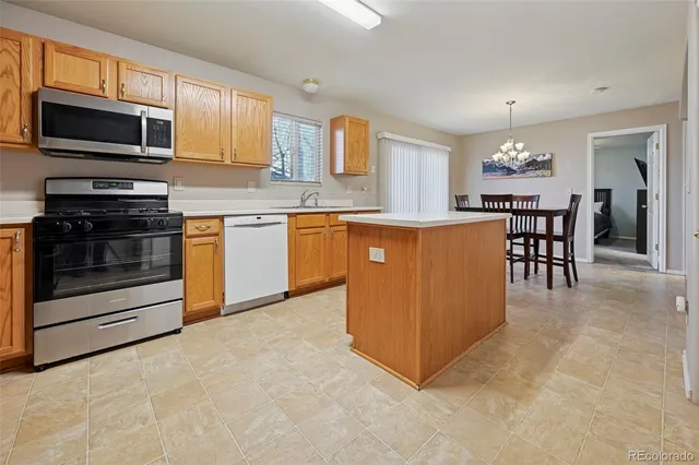 a kitchen with stainless steel appliances granite countertop a stove top oven a sink dishwasher a dining table and chairs with wooden floor