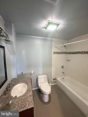 a bathroom with a granite countertop sink mirror vanity and toilet