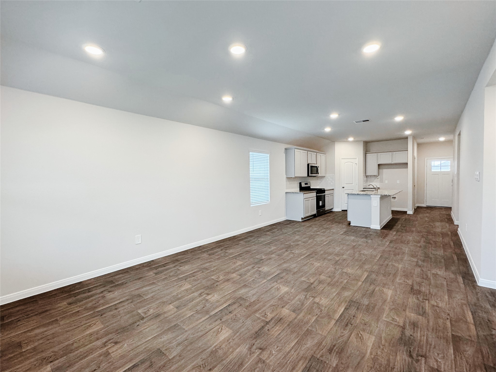 204 Addison Place Lockhart, TX 78644 - Photo 10 of 39 Unfurnished living room featuring recessed lighting, dark wood-type flooring, and healthy amount of natural light