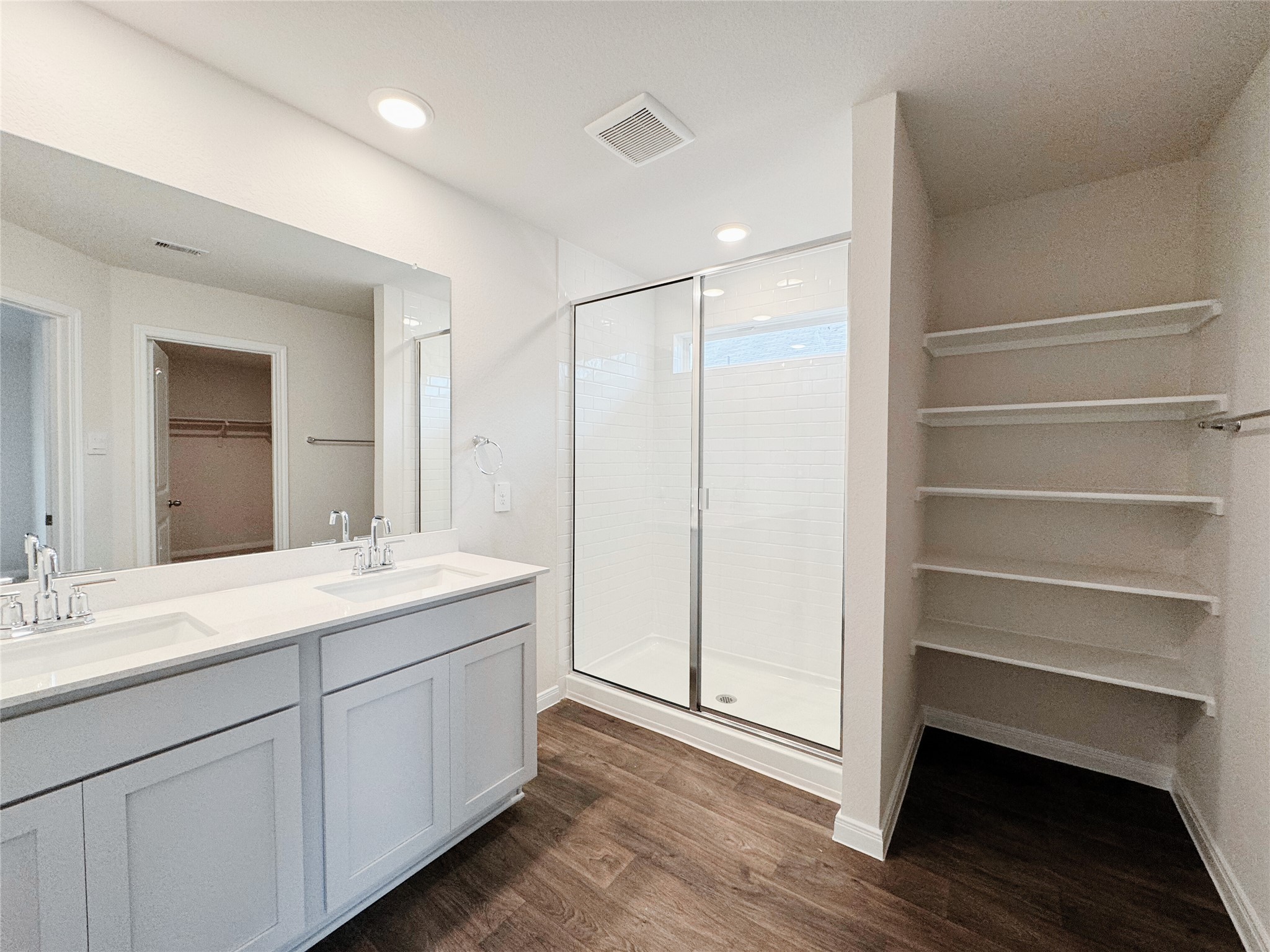 204 Addison Place Lockhart, TX 78644 - Photo 15 of 39 Bathroom featuring a spacious closet, a stall shower, double vanity, dark wood-type flooring, and recessed lighting