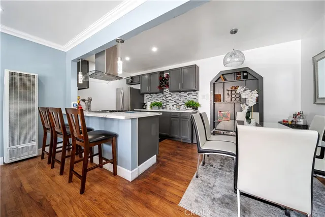 a living room with furniture a wooden floor and kitchen view