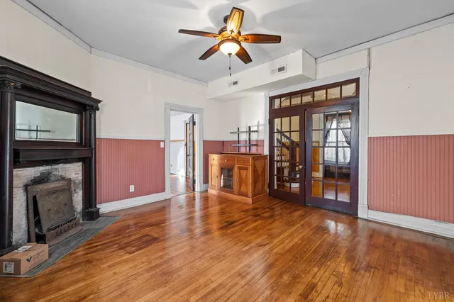 a view of a livingroom with a fireplace wooden floor a ceiling fan a fireplace and windows