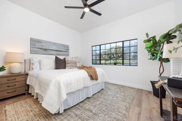 a bedroom with a bed potted plant on the dresser and a window