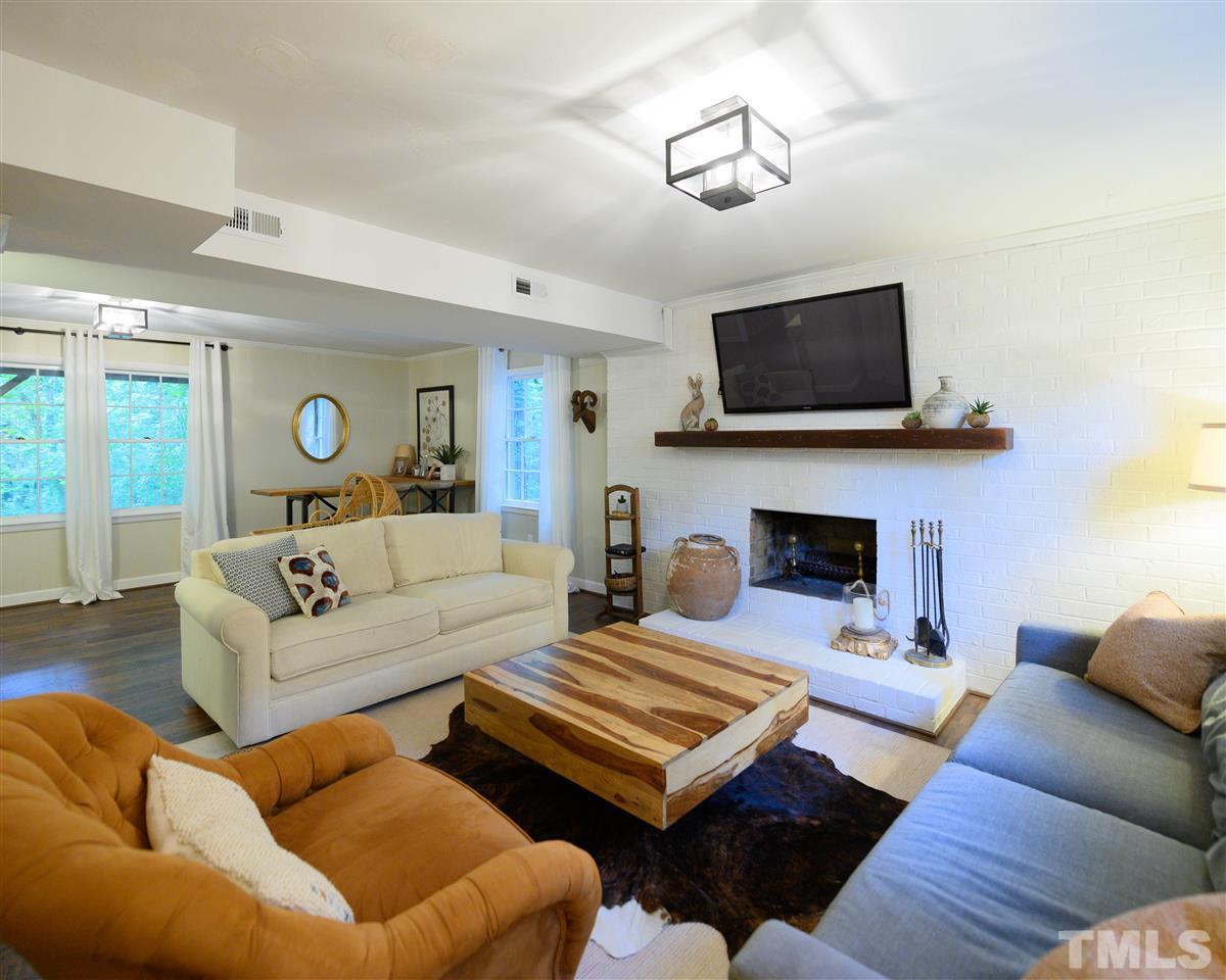 4917 Oak Park Road Raleigh, NC 27612 - Photo 16 of 25 a living room with furniture a flat screen tv and a fireplace