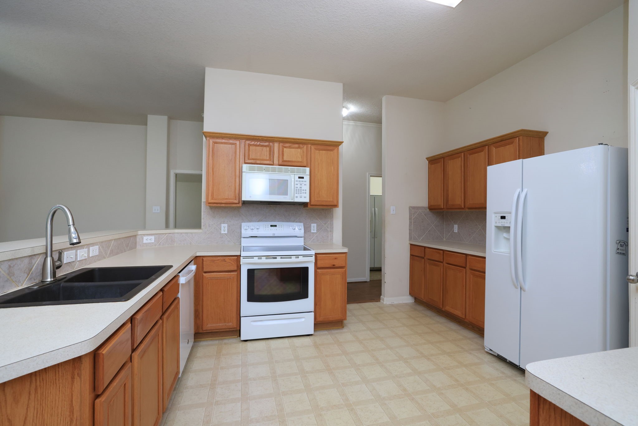 30515 Red Bluff Circle Magnolia, TX 77355 - Photo 12 of 28 This kitchen features white countertops, ample wooden cabinetry, and plenty of counter space for meal prep. It has a spacious layout with a double sink and neutral tile flooring.