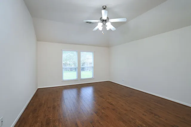 a view of an empty room with wooden floor and a window