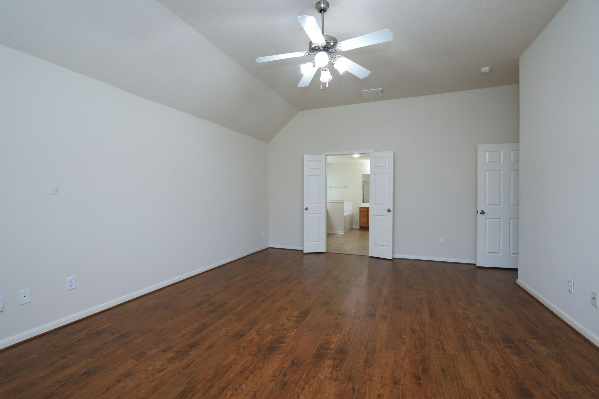 30515 Red Bluff Circle Magnolia, TX 77355 - Photo 16 of 28 This spacious room features laminate wood floors, neutral walls, and a ceiling fan. It includes double doors leading to an adjoining area, providing a versatile layout ideal for a bedroom or living space.