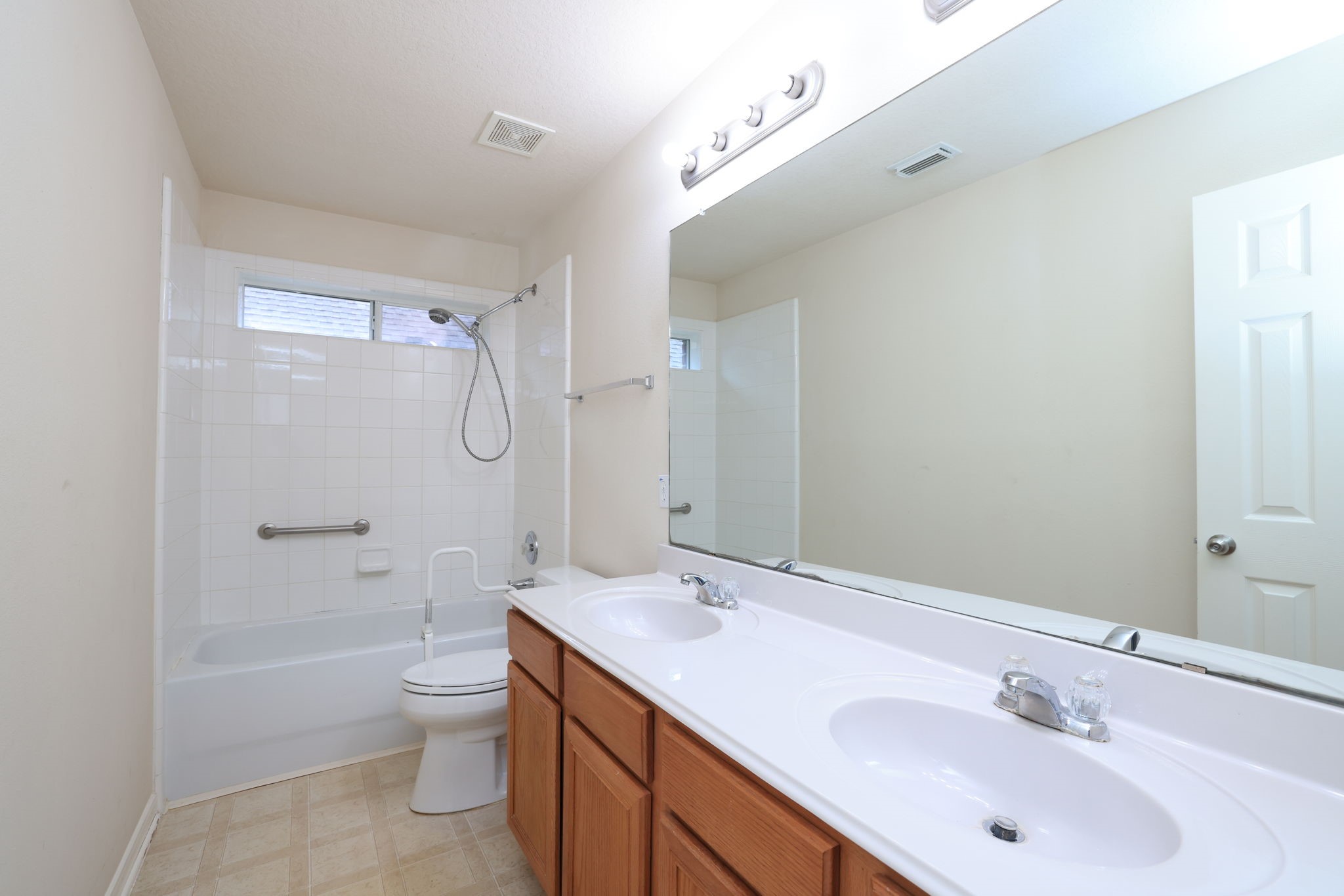 30515 Red Bluff Circle Magnolia, TX 77355 - Photo 22 of 28 This bathroom features a spacious layout with a double sink vanity, a full bathtub with shower, and neutral tile flooring. It includes a large mirror and a window for natural light.