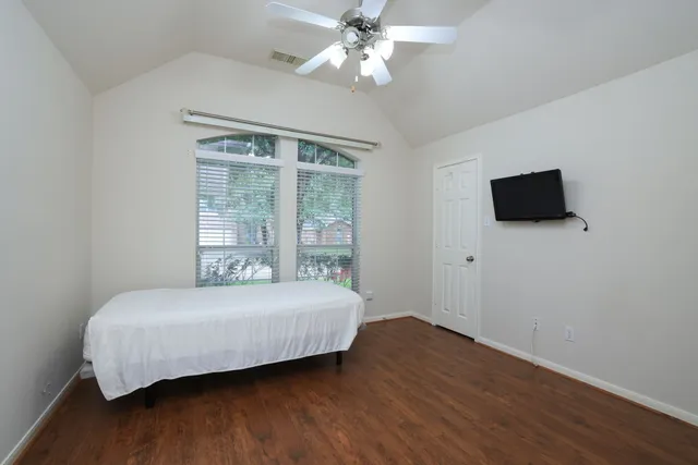 a bedroom with a bed and a flat tv screen on dresser