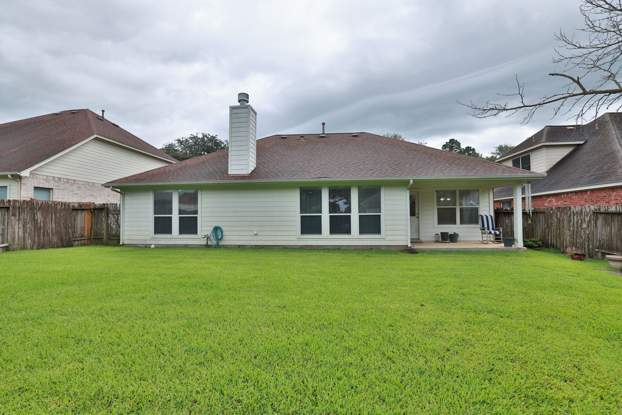 30515 Red Bluff Circle Magnolia, TX 77355 - Photo 27 of 28 This photo shows the back of a single-story house with a spacious, well-maintained lawn. Covered patio area, ideal for outdoor relaxation. It's enclosed by a wooden fence, offering privacy.