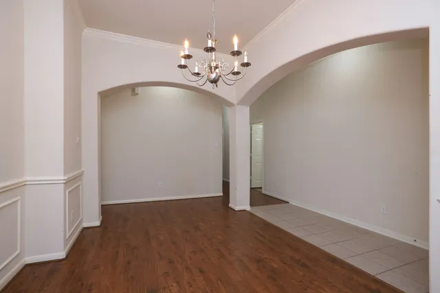 an empty room with wooden floor and chandelier