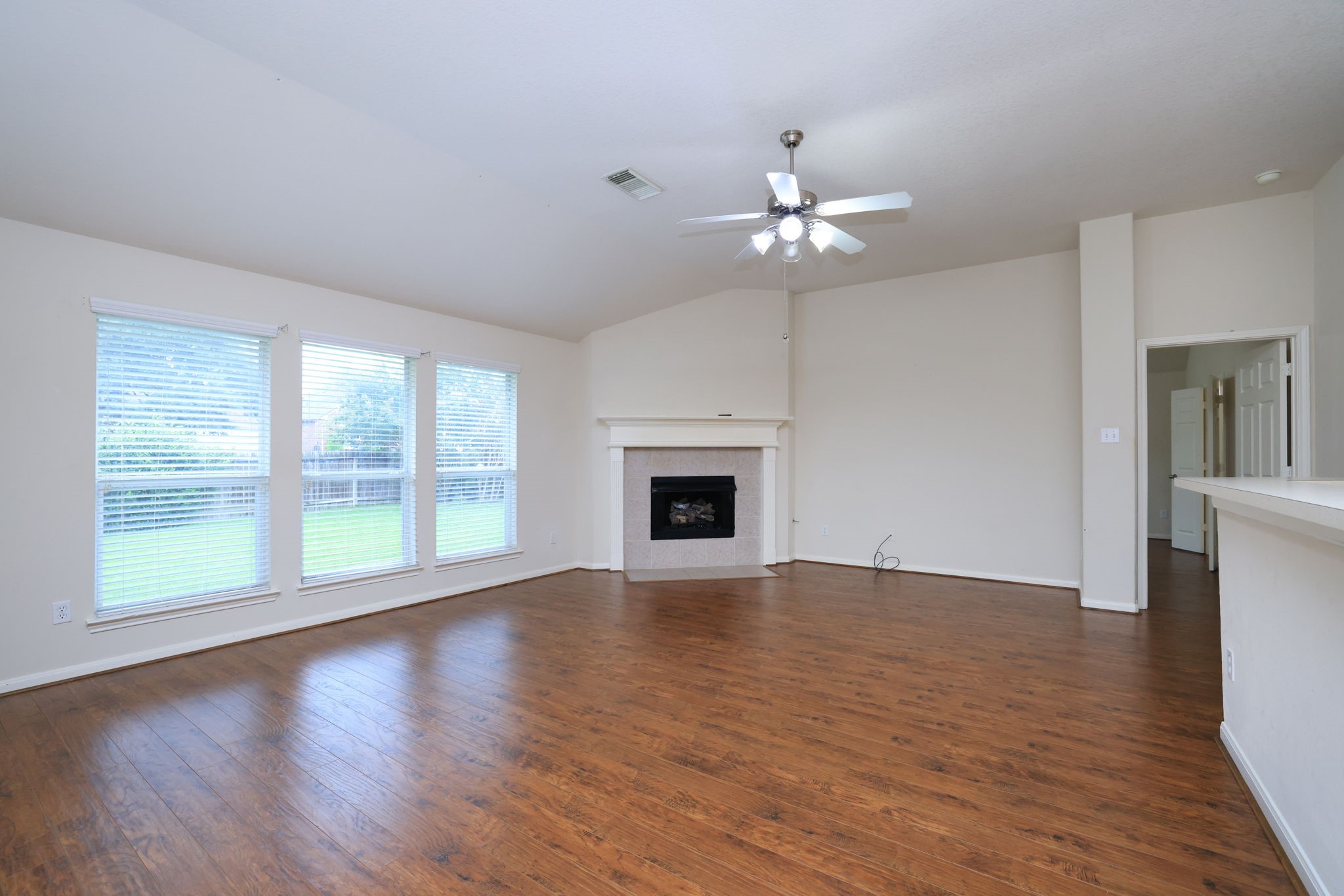 30515 Red Bluff Circle Magnolia, TX 77355 - Photo 9 of 28 This spacious family room features laminate wood floors, a cozy fireplace, and large windows that offer plenty of natural light. The high ceiling and neutral walls provide an open and airy feel, perfect for a welcoming home environment.