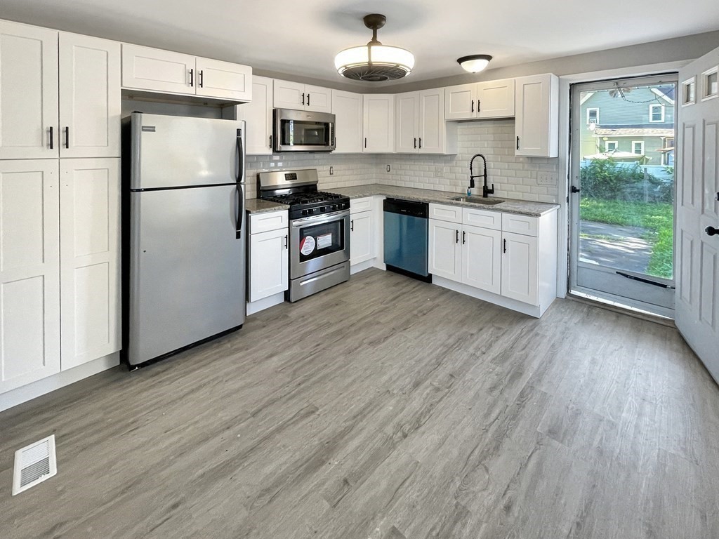 12 Ladd Street Springfield, MA 01109 - Photo 21 of 37 a kitchen with stainless steel appliances granite countertop a refrigerator a stove a sink dishwasher and white cabinets with wooden floor