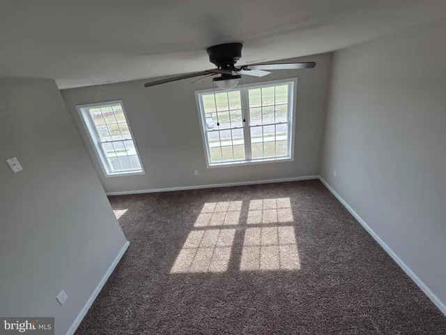 an empty room with windows and ceiling fan