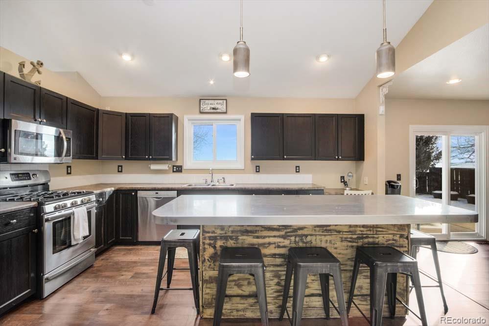 2031 Prairie View Court Fort Collins, CO 80526 - Photo 7 of 33 a kitchen with stainless steel appliances granite countertop a sink a stove a microwave a center island and chairs