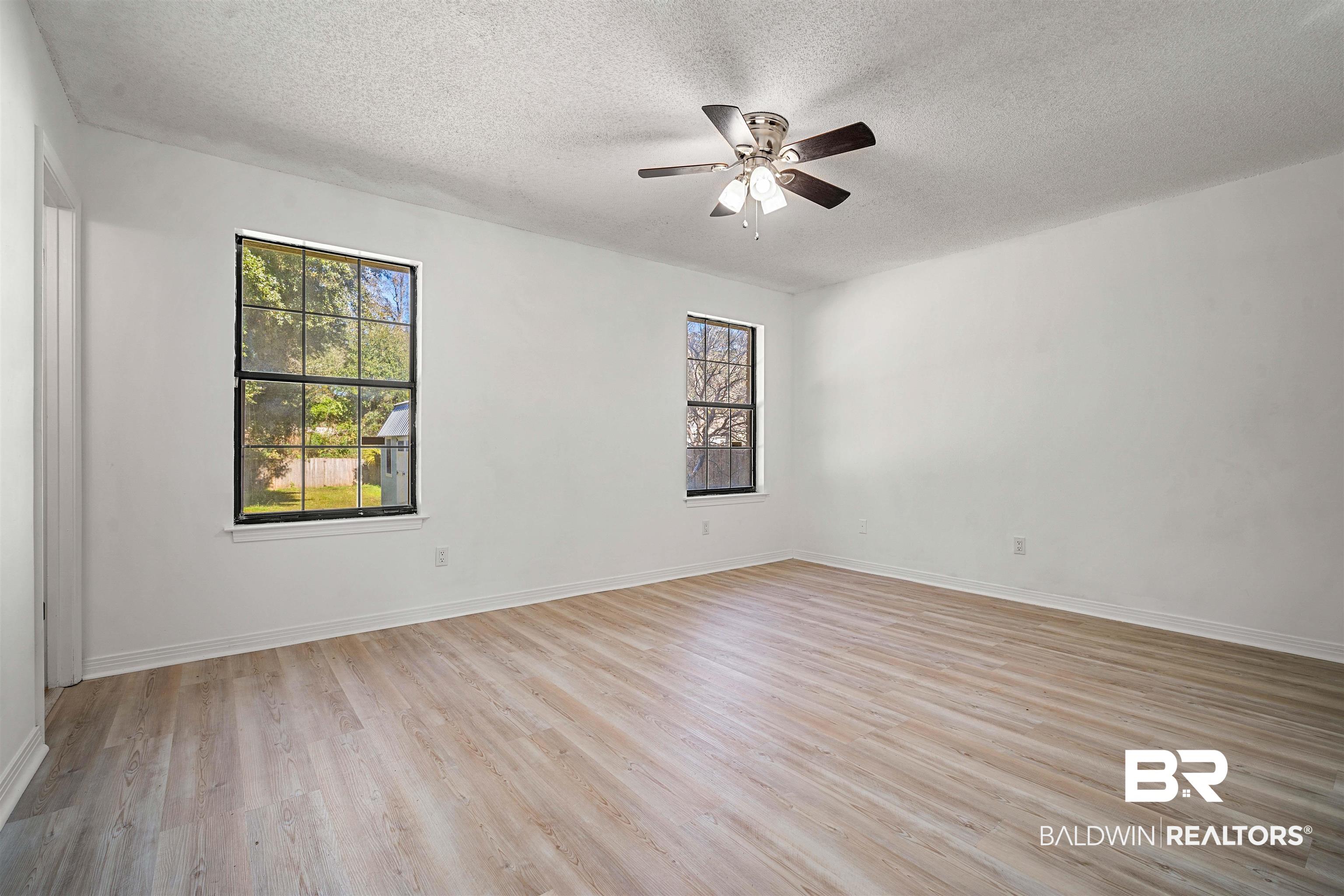 12910 Del Rio Street Grand Bay, AL 36541 - Photo 14 of 26 Empty room featuring plenty of natural light, light wood-type flooring, a textured ceiling, and ceiling fan