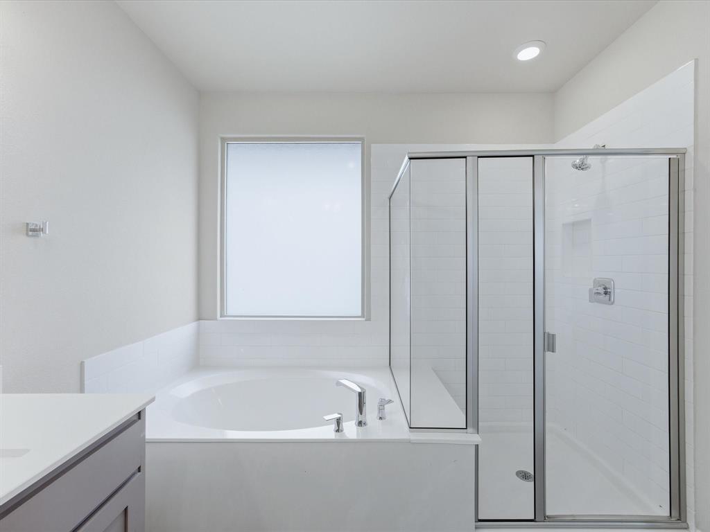 1121 Knightsbridge Road Argyle, TX 76226 - Photo 11 of 39 Primary bathroom featuring a built-in soaking tub, a separate glass-enclosed shower with subway tile, a frosted window, recessed lighting, and a vanity with a light-toned countertop