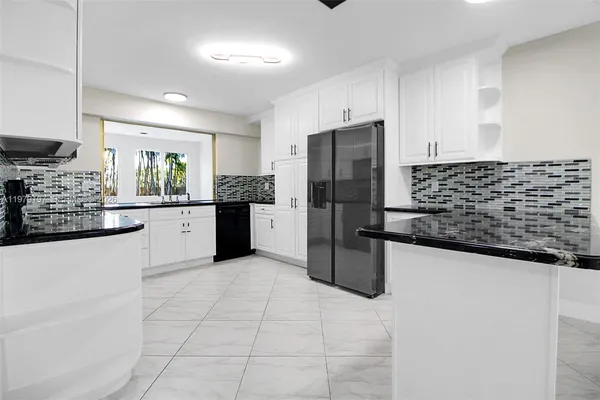 a kitchen with granite countertop a refrigerator and a stove top oven