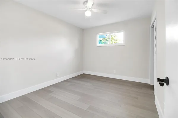 an empty room with a window and a fan