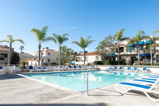 a swimming pool that has lawn chairs and a dining table under an umbrella