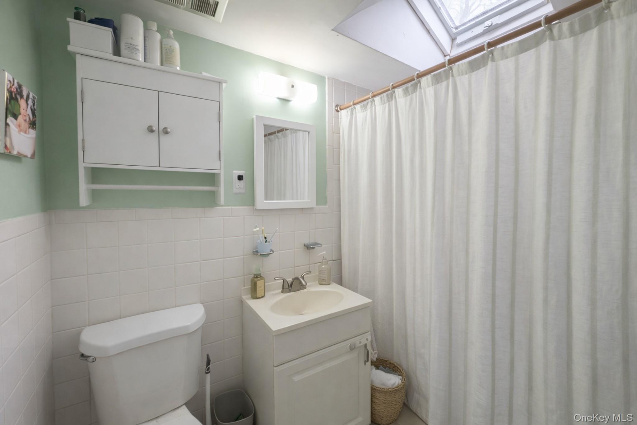 17 Oneida Avenue Selden, NY 11784 - Photo 10 of 12 a bathroom with a sink a toilet and shower curtain