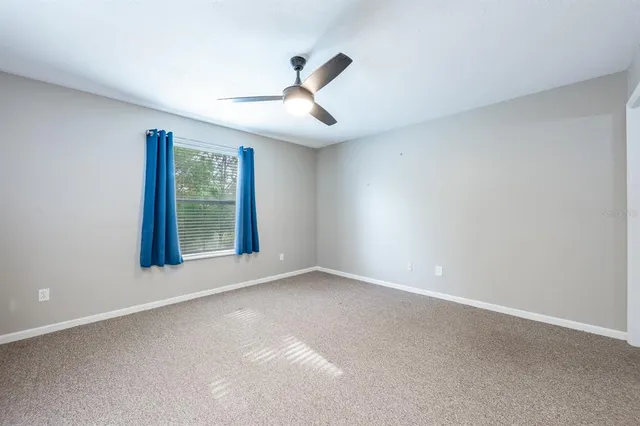 an empty room with windows and ceiling fan