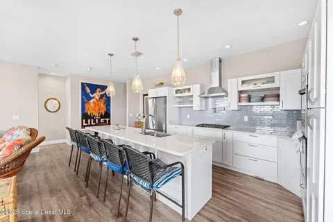 a kitchen with stainless steel appliances granite countertop a stove a sink a dining table and chairs with wooden floor