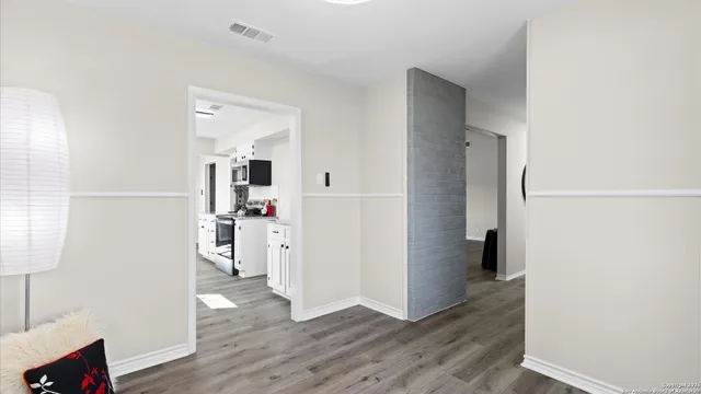 a view of a kitchen from the hallway with a room and wooden floor