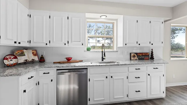 a kitchen with white cabinets and window